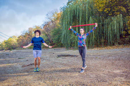 Sports couple training outdoors -Young woman working out with resistance bandsの写真素材