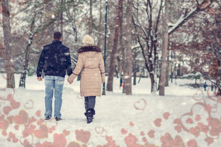 valentines holiday - young beautiful couple having a walk in winter park