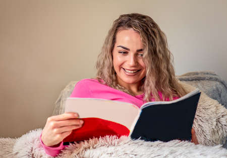 beautiful happy girl reading a magazine at homeの写真素材