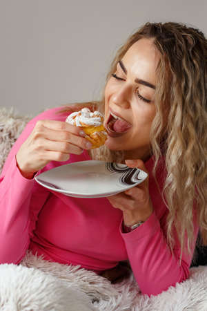 smiling enjoys girl eating cookie sitting on a couch at homeの写真素材