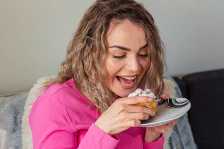 happy smiling girl eating cookie sitting on a couch at home