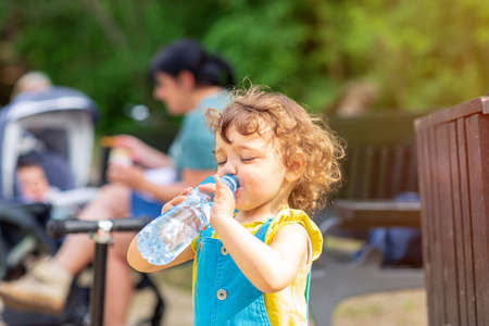 little cute girl drinking water from the bottle in parkの写真素材