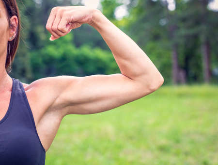 Fit muscular young woman - strong bodybuilder outdoorの写真素材
