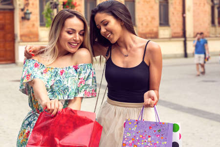 Happiness, friends, sale and fun concept - Young girls with shopping bags in the city.の写真素材