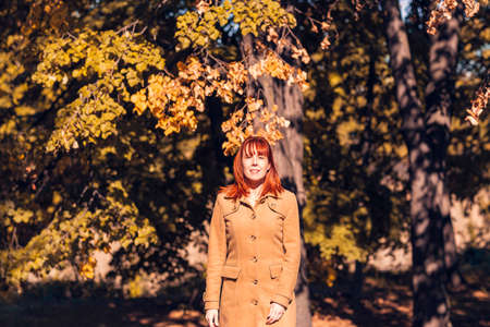 sunny autumn park. Portrait of Cute ginger girl in natureの写真素材