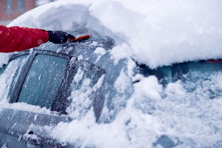 Snow covered car.Man removing snow from car in winter