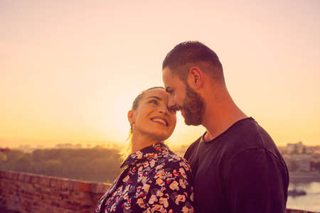 cheerful young couple kissing outdoor at the sunsetの写真素材