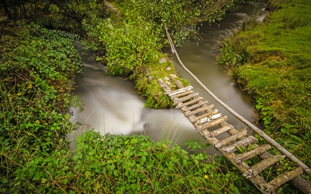 Small rural footbridge crossing a twisted creekの写真素材