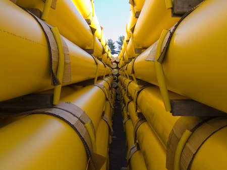 a stack of yellow natural gas utility pipes in a utility company yardの写真素材