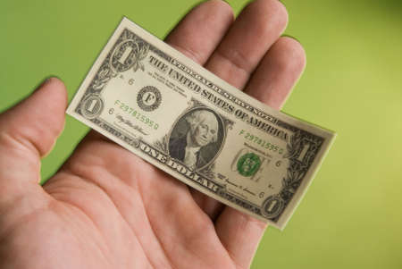 a hand holding a miniature United States one dollar bill depicting the shrinking United States...