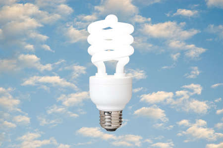a compact fluorescent light bulb against a blue sky with cloudsの写真素材