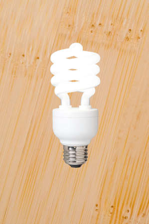 a compact fluorescent light bulb against a bamboo flooring backgroundの写真素材