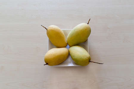 Mangos on a white square plate with wooden background