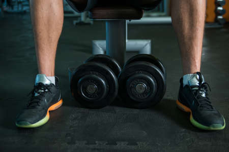 Feet and dumbbells in modern gym during fitness trainingの写真素材