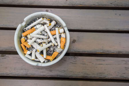 Various cigarette butts in dirty full ashtrayの写真素材