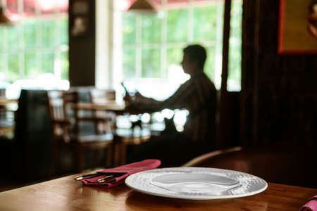Wooden table at restaurant served with plate, fork, knife and napkinsの写真素材