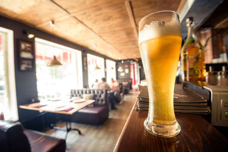 Glass of light beer on a table between empty glasses on front bar in pubの写真素材