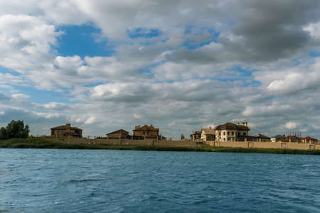 Summer beautiful landscape with river, blue sky, clouds and elite cottage area