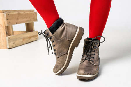 Detail of standing woman wearing fashionable brown boots posing on white