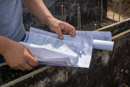 Closeup of man's hands holding blueprints at construction site