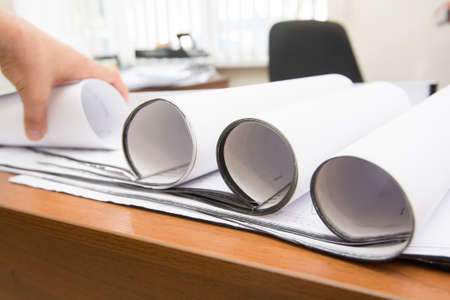 Closeup of man's hands holding blueprints at construction siteの写真素材