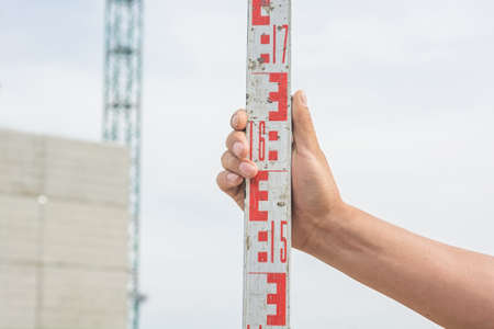 Hand holding level staff, also called levelling rod, is a graduated wooden or aluminum rod, the use...