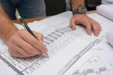 Closeup of man's hands holding blueprints at construction site