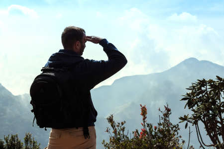 Backpacker looking at misty mountains