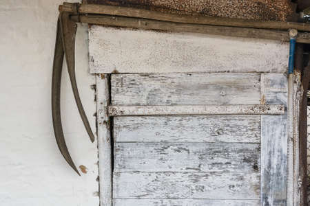 Rusted metal scythes hang above door inside houseの写真素材