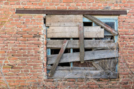 Old boarded-up window on brick wallの写真素材