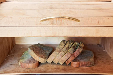 Slices of old moldy rye bread on wooden shelfの写真素材