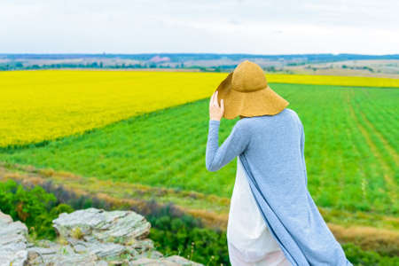 Back view of young woman in nature with fieldsの写真素材