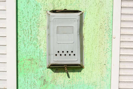 Old metal mailbox hangs on green wallの写真素材