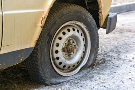 Flat tire of an old car on roadの写真素材