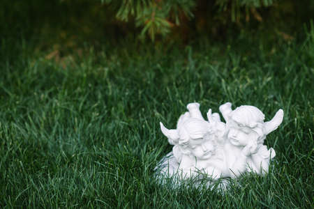Small white figurine of two angels in grass