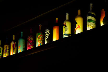 Colorful bottles stay on shelf in darkの写真素材