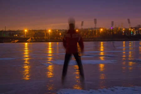 Young man on frozen river at nightの写真素材