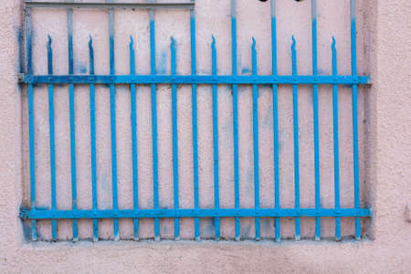 Close up blue metal grid mounted in pink wallの写真素材