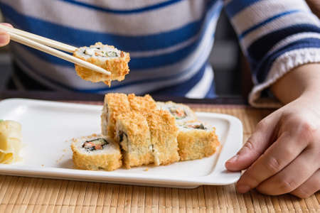 Young woman eats sushi rolls with chopsticksの写真素材