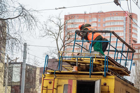 Worker in uniform on top electrical service truckの写真素材