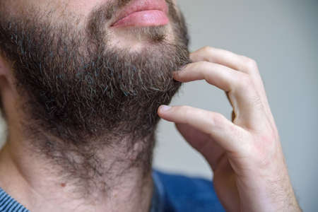 Close up male hand touches his beard