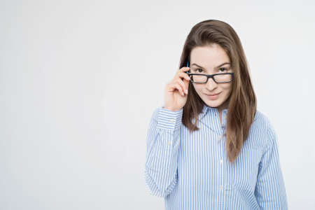 Pretty young girl touches glasses looks at camera
