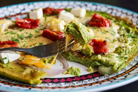 Spinach omelette with tomatoes and cheese on top