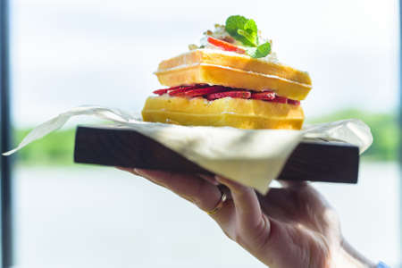 Close up hand holds Belgian waffles on trayの写真素材