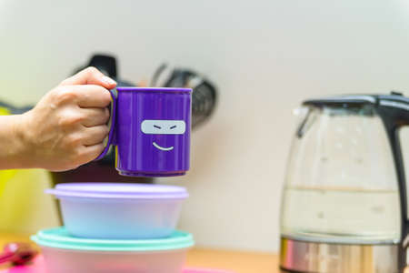 Hand holds plastic cup with smiling faceの写真素材