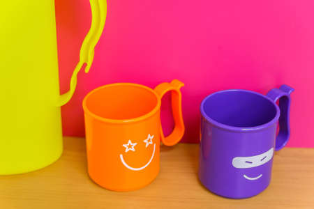 Two bright plastic cups with funny faces on themの写真素材