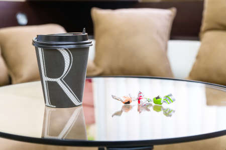 Paper cup of coffee on table with two candiesの写真素材