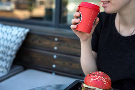 Close up young woman drinks coffee from paper cupの写真素材