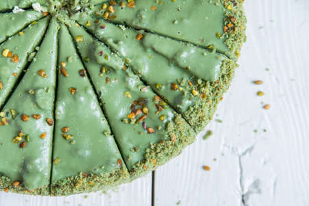 Pistachio cake sliced on white wooden background