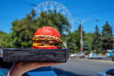 Hand holds restaurant burger on wooden boardの写真素材